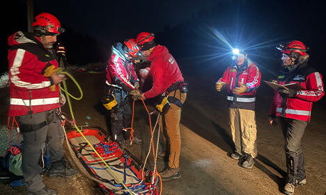 Kamloops Search and Rescue volunteers conducting nighttime rescue training with ropes, stretcher, and headlamps