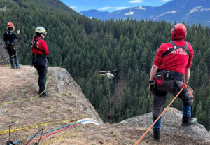 Kamloops Search and Rescue team performing cliffside helicopter hoist rescue training in forested mountain terrain