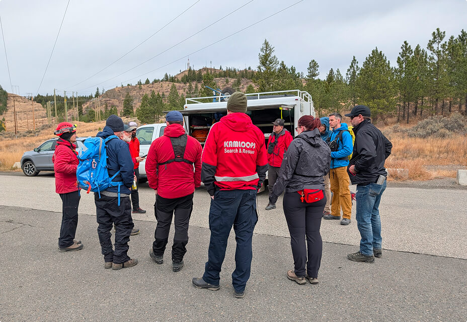 Kamloops Search and Rescue volunteers gathered for field briefing beside rescue truck before training exercise